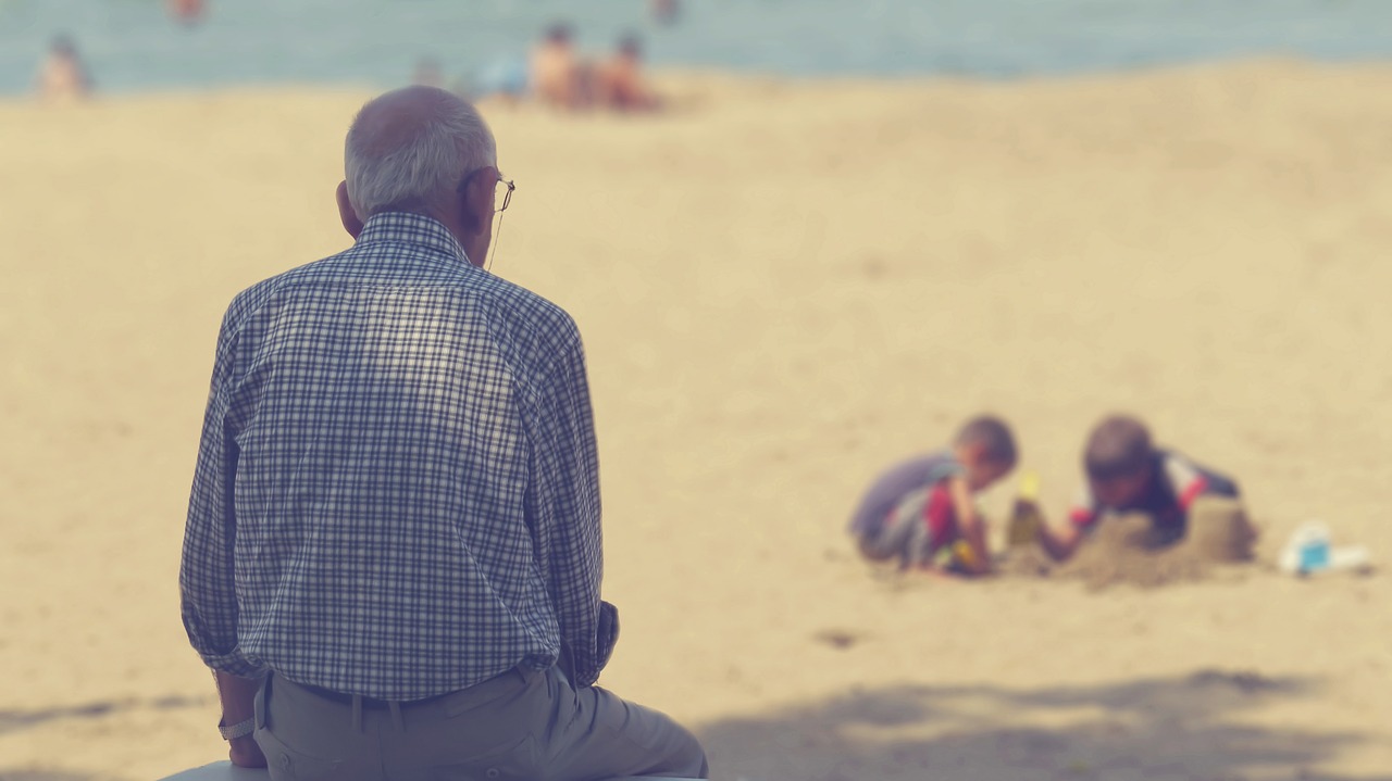 砂場で遊ぶ子供を見守る老人